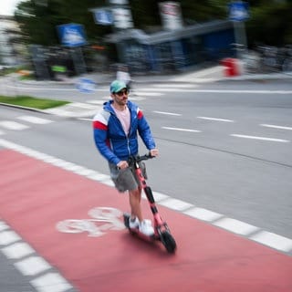 Ein Mann ist mit einem einem E-Scooter auf einem Fahrradweg in Hamburg unterwegs. (zu: "Heidelberg will strengere Regeln für E-Scooter")