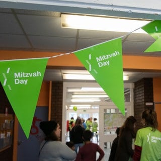 Grüne Fahnen mit der Aufschrift "Mitzvah Day" hängen in einem Gang. (Archivbild)