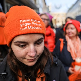 Eine Frau mit einer Mütze mit der Aufschrift "Keine Gewalt gegen Frauen und Mädchen"