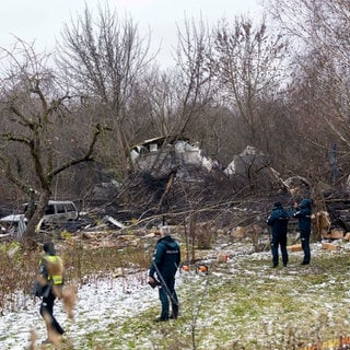 Mitarbeiter des litauischen Katastrophenschutzministeriums und Polizeibeamte stehen in der Nähe der Stelle, an der ein DHL-Frachtflugzeug in ein Haus nahe der litauischen Hauptstadt Vilnius, Litauen, gestürzt ist.