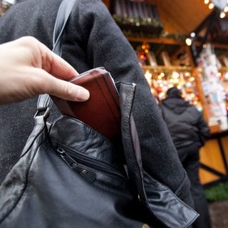 Jemand zieht auf dem Weihnachtsmarkt einer Besucherin die Geldbörse aus der Handtasche: Mit der Aktion "Gelbe Hand" will die Polizei in Heidelberg auf Taschendiebe aufmerksam machen. 