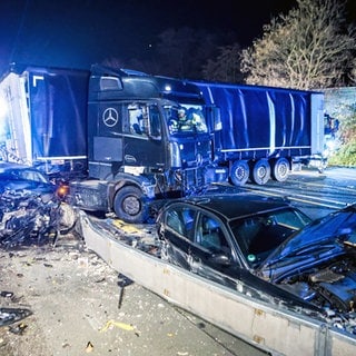 Ein Lastwagen steht auf der Autobahn 1 bei Hagen an der Unfallstelle neben beschädigten Autos. Nach einer Chaosfahrt über mehrere Autobahnen hat die Polizei in Nordrhein-Westfalen einen auffälligen Lkw-Fahrer aus dem Verkehr gezogen. Es habe mehrere Unfälle und Sachschäden gegeben, wie die Polizei mitteilte.