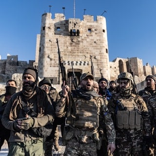 Mitglieder der bewaffneten syrischen Oppositionskräfte stehen vor der antiken Burg in Aleppo in Syrien.