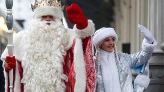 Väterchen Frost (der Weihnachtsmann in Russland) und das Schneemädchen winken.