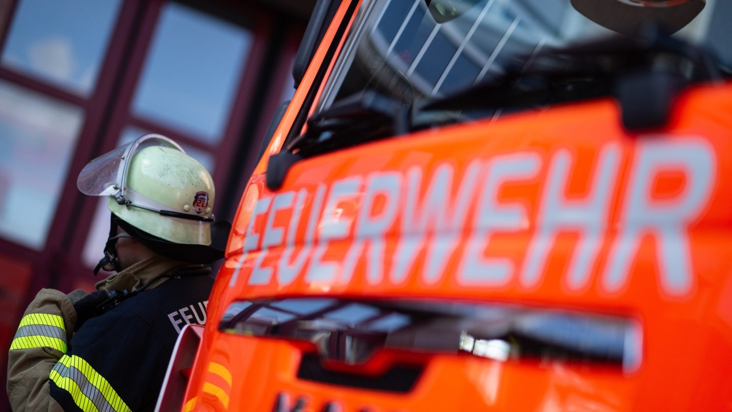 Ein Feuerwehrmann mit einem Feuerwehrauto. Peinliche Geschichte in Kaiserslautern. Zwei Jugendlichen kamen nach dem Einbruch in ein Schwimmbad nicht mehr aus dem Becken und mussten den Notruf wählen.