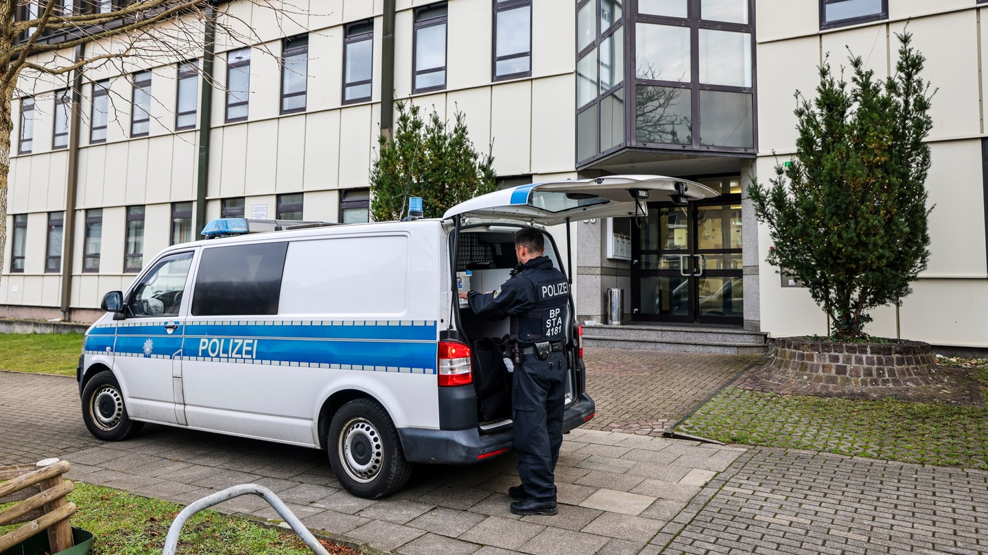 Ein Polizeibeamter der Bundespolizei steht an einem Polizeiauto vor einer Flüchtlingsunterkunft in Essen.