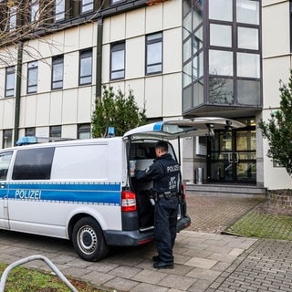 Ein Polizeibeamter der Bundespolizei steht an einem Polizeiauto vor einer Flüchtlingsunterkunft in Essen.