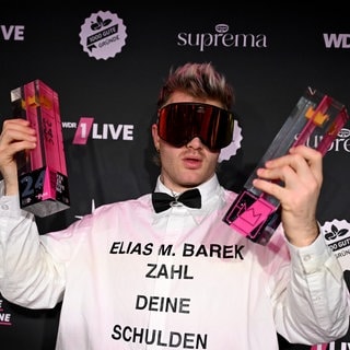 Sänger Ski Aggu zeigt nach der Verleihung des Musikpreises "1Live Krone" seine beiden Preise.