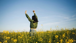 Symbolfoto: Junge Frau in Feld mit Blumen