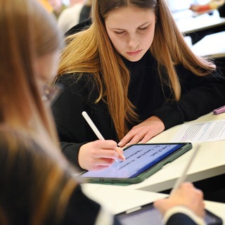 Schüler sitzen in der Schule und lernen am Tablet