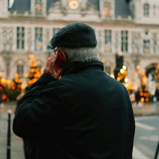 Senior telefoniert auf dem Weihnachtsmarkt 