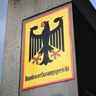 in Hinweisschild mit Bundesadler und dem Schriftzug Bundesverfassungsgericht. Das Bundesverfassungsgericht soll gestärkt und geschützt werden - zum Beispiel vor Extremisten. Dafür muss das Grundgesetz geändert werden.