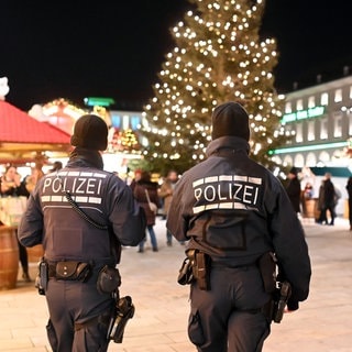 Polizisten gehen über den Weihnachtsmarkt. Nach dem mutmaßlichen Anschlag auf Weihnachtsmarkt in Magdeburg ist in Baden-Württemberg mehr Polizei unterwegs.