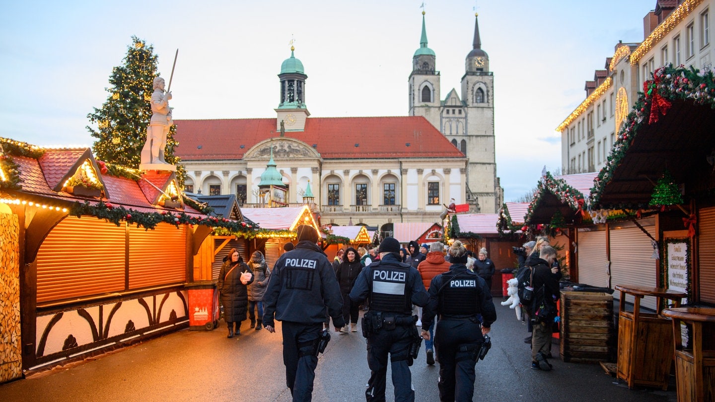 Polizisten und Passanten gehen über den geschlossenen Weihnachtsmarkt in Magdeburg. Nach der Attacke am 20. Dezember gibt es Kritik am Sicherheitskonzept auf dem Weihnachtsmarkt.