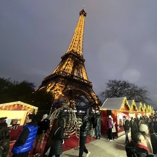 Der Eiffelturm in Paris. Im Vordergrund sieht man einen gerade stattfindenden Weihnachtsmarkt.