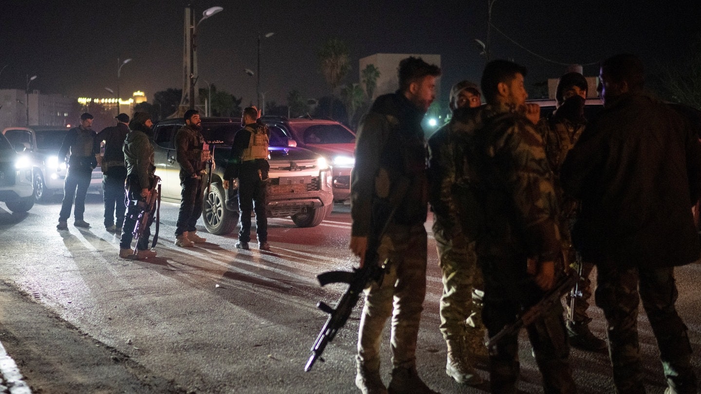 Syrische Kämpfer versammeln sich in der Nacht auf einer Straße in Damaskus.