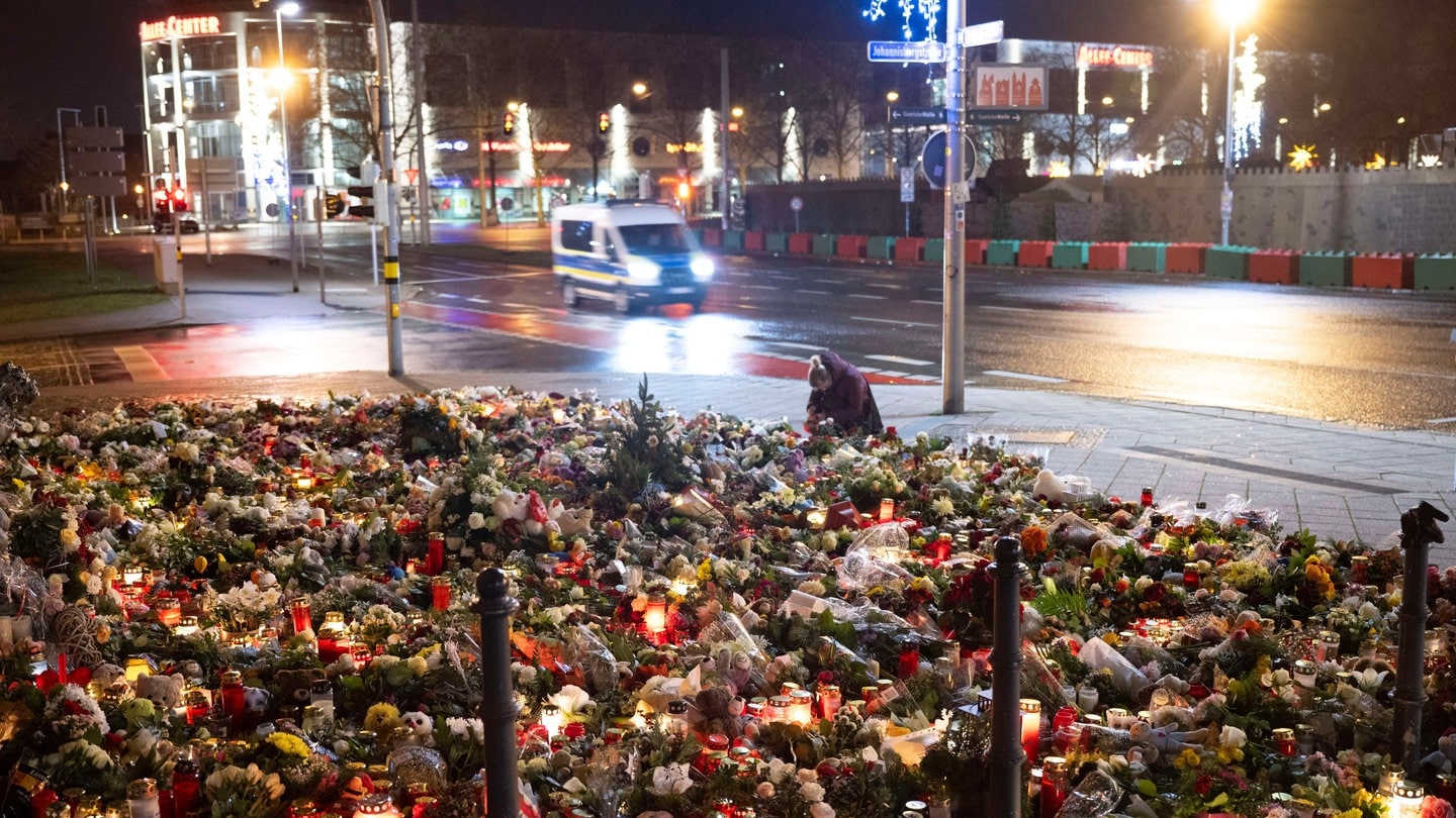 Zahlreiche Kerzen, Blumen und Kränze liegen beziehungsweise stehen vor dem Eingang der Johanniskirche. Am 20. Dezember 2024 ist auf dem Weihnachtsmarkt in Magdeburg ein Autofahrer in eine Menschengruppe gefahren. Es gab mehrere Tote und Verletzte.