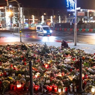 Zahlreiche Kerzen, Blumen und Kränze liegen beziehungsweise stehen vor dem Eingang der Johanniskirche. Am 20. Dezember 2024 ist auf dem Weihnachtsmarkt in Magdeburg ein Autofahrer in eine Menschengruppe gefahren. Es gab mehrere Tote und Verletzte.