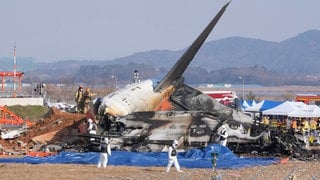 Feuerwehrleute und Mitglieder eines Rettungsteams arbeiten in der Nähe des Wracks eines Passagierflugzeugs am Muan International Airport. 