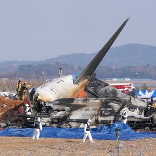 Feuerwehrleute und Mitglieder eines Rettungsteams arbeiten in der Nähe des Wracks eines Passagierflugzeugs am Muan International Airport. 