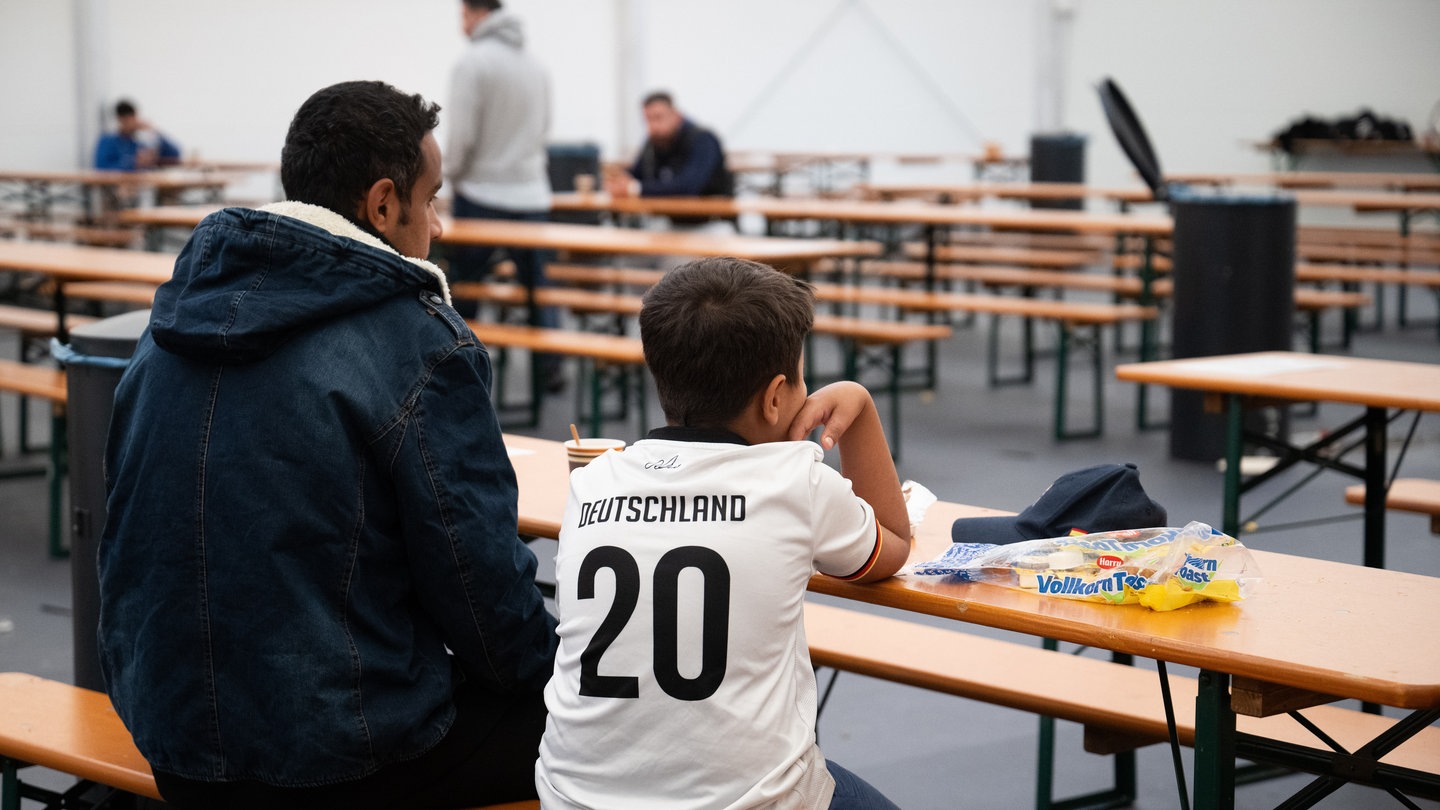 Mansour El-Dschaber (l) und sein Sohn Abd El-Rauuf aus Syrien sitzen im Ankunftszentrum am ehemaligen Flughafen Tegel im Essensbereich.