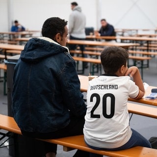 Mansour El-Dschaber (l) und sein Sohn Abd El-Rauuf aus Syrien sitzen im Ankunftszentrum am ehemaligen Flughafen Tegel im Essensbereich.