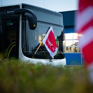 Eine ver.di-Fahne hängt an einem geparkten Linienbus.