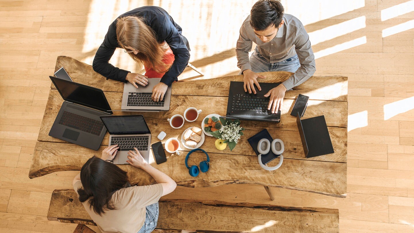 Das Team eines Start Ups sitzt zusammen am Tisch und arbeitet