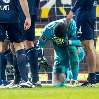 Torwart Patrick Drewes (2.v.r) vom VfL Bochum kniet am Boden, nachdem er mit einem Gegenstand am Kopf getroffen wurde. (zu dpa: «DFB-Sportgericht verhandelt Feuerzeugwurf von Berlin»)