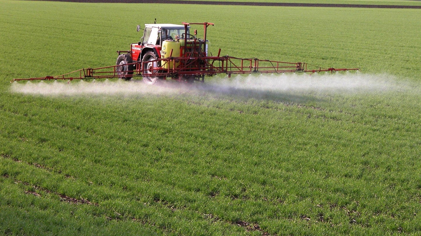 Traktor versprüht Chemikalien auf einem Feld: Landwirte in ganz Deutschland lassen prüfen, ob ihre Parkinson-Erkrankung durch Pestizide ausgelöst wurde.