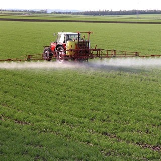 Traktor versprüht Chemikalien auf einem Feld: Landwirte in ganz Deutschland lassen prüfen, ob ihre Parkinson-Erkrankung durch Pestizide ausgelöst wurde.