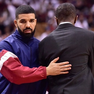 Der kanadische Rapper Drake (l) gibt Dwane Casey, Trainer von Toronto, beim Verlassen des Spiels, zwei Minuten vor Ende der Partie, einen Klaps auf den Rücken. Foto: Frank GunnThe Canadian PressAPdpa