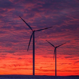 Windräder stehen vor leuchtenden Wolken zum Sonnenuntergang. Eine aktuelle Analyse zeigt: Es wurde so viel Strom aus erneuerbaren Energien gewonnen, wie noch nie zuvor in der EU.