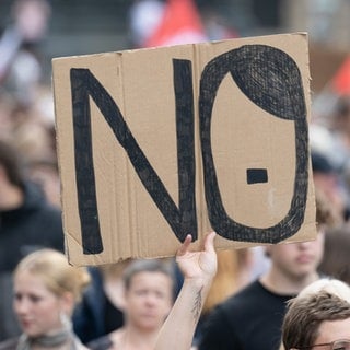 Teilnehmer einer Demonstration gegen Rechtsextremismus und für Demokratie halten ein Schild mit der Aufschrift „NO“. 