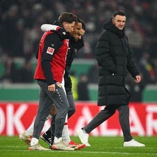 Fußball, DFB-Pokal, VfB Stuttgart - FC Augsburg, Viertelfinale, MHPArena, Stuttgarts Enzo Millot (2.vl) geht nach dem Spiel verletzt unter den Augen von Stuttgarts Sportdirektor Christian Gentner (r) vom Platz. WICHTIGER HINWEIS: Gemäß den Vorgaben der DFL Deutsche Fußball Liga bzw. des DFB Deutscher Fußball-Bund ist es untersagt, in dem Stadion undoder vom Spiel angefertigte Fotoaufnahmen in Form von Sequenzbildern undoder videoähnlichen Fotostrecken zu verwerten bzw. verwerten zu lassen.