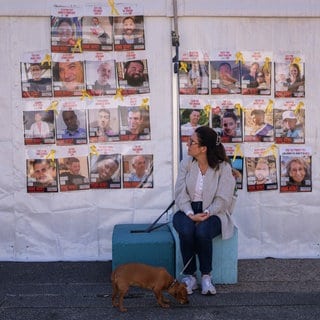 Eine Frau betrachtet Plakate mit Geiseln, als sie die Live-Übertragung der Übergabe von weiteren Geiseln durch die Hamas an Vertreter des Roten Kreuzes im Rahmen der Waffenruhevereinbarung zwischen Israel und der Hamas verfolgt. (Archivbild)