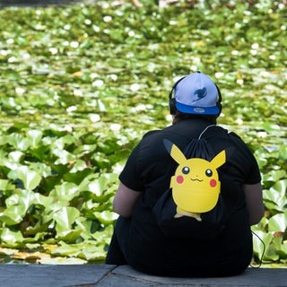 Ein Pokémon-Fan sitzt in einem Park. Das Spiel "Pokémon Go" soll wohl verkauft werden.