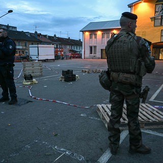 Ein Polizist und ein Soldat stehen am Ort eines Messerangriffs. Nach einem Angriff im elsässischen Mulhouse mit einem Toten und mehreren Verletzten hat die französische Anti-Terror-Staatsanwaltschaft die Ermittlungen übernommen.