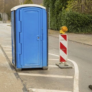 Blaue tragbare Toilette steht auf einer Straße