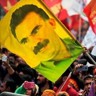 Ein Jugendlicher hält eine Fahne mit dem Bild des inhaftierten Anführers der verbotenen kurdischen Arbeiterpartei PKK, Öcalan. Öcalan hat seine Anhänger dazu aufgerufen, die Waffen niederzulegen.