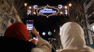 Zwei Frauen fotografieren mit ihren Handys die "Happy Ramadan"-Beleuchtung in Frankfurt am Main