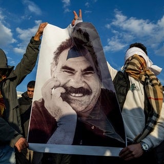 Jugendliche halten ein Plakat des inhaftierten Anführers der Arbeiterpartei Kurdistans (PKK), Öcalan, während sie live auf einem Fernsehbildschirm mitverfolgen, wie Mitglieder einer prokurdischen Delegation der Partei für Gleichheit und Demokratie (DEM) eine Erklärung von Öcalan veröffentlichen.