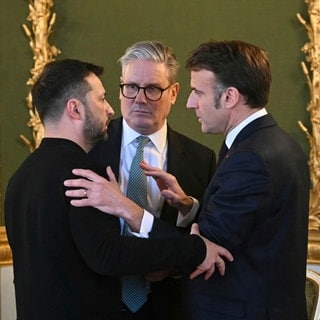 Der ukrainische Präsident Wolodymyr Selenskyj, der britische Premier Sir Keir Starmer und der französische Präsident Emmanuel Macron umarmen sich. - Großbritannien und Frankreich haben eine Waffenruhe in der Ukraine vorgeschlagen.