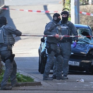 Beamte des Entschärfungsdienstes der Polizei sind an einem beschädigten Fahrzeug an einer Zufahrt zur Rheinbrücke im Einsatz. Nach einem Vorfall mit einem Auto in der Mannheimer Innenstadt mit mindestens einem Toten und mehreren Verletzten ist der mutmaßliche Fahrer nach Polizeiangaben festgenommen worden. Nach Polizeiangaben war ein Fahrzeug in eine Menschenmenge gefahren.