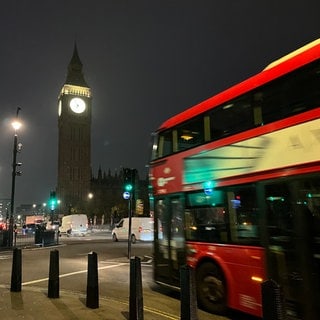 Ein Bus fährt in London am Elizabeth Tower mit der Glocke Big Ben vorbei.