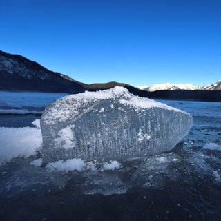 Ein Eisbrocken liegt auf dem mit einer Eisdecke überzogenen Eibsee unter strahlend blauem Himmel. (zu dpa: «Mehrere Menschen auf zugefrorenem See durchs Eis gebrochen»)